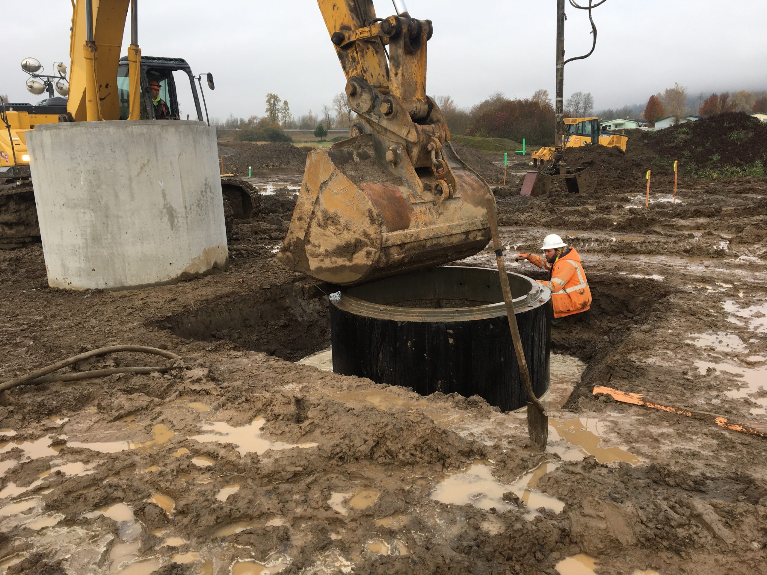 excavator pushes lift station wet well into ground