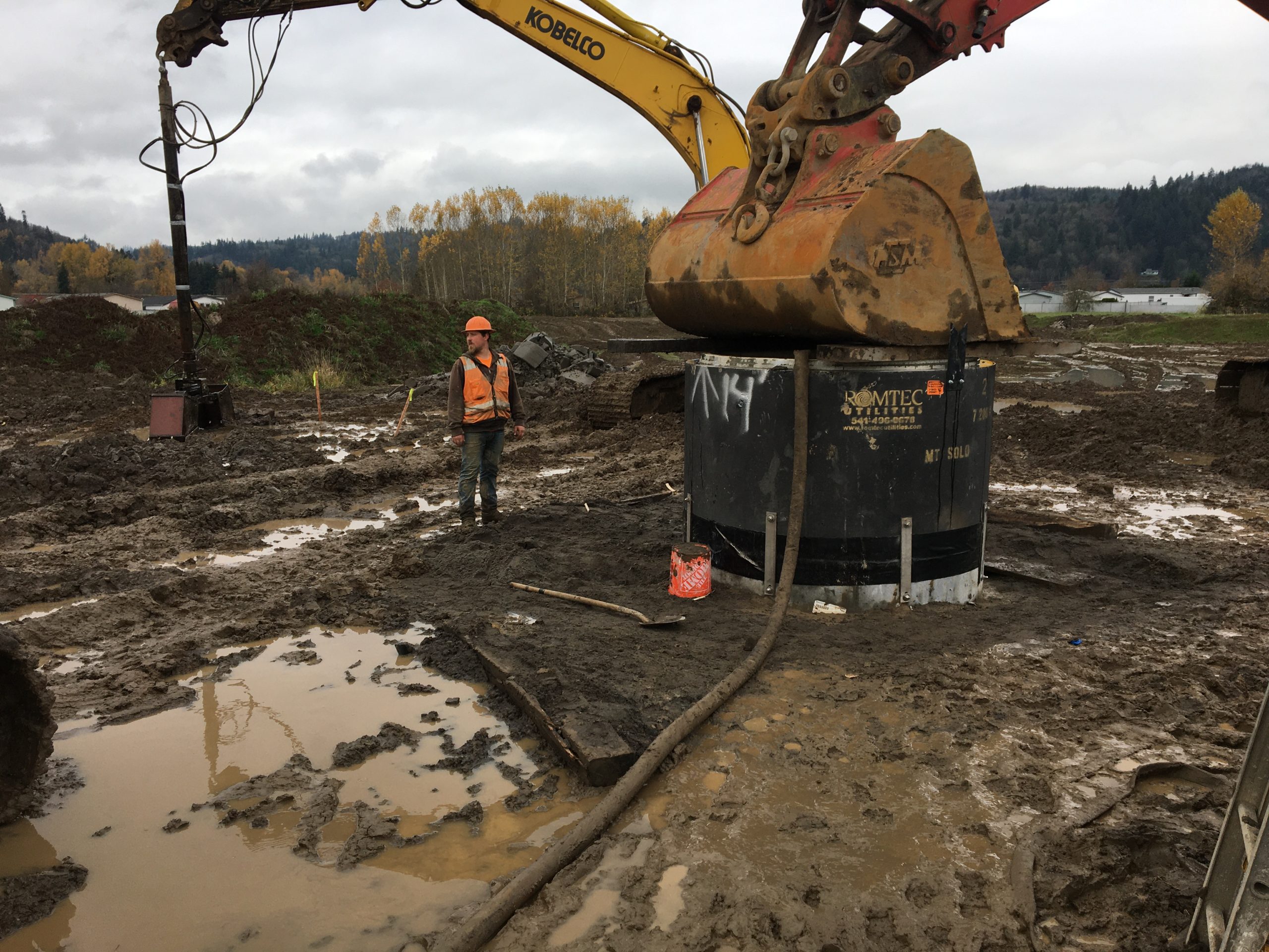 excavator pushing wet well into place